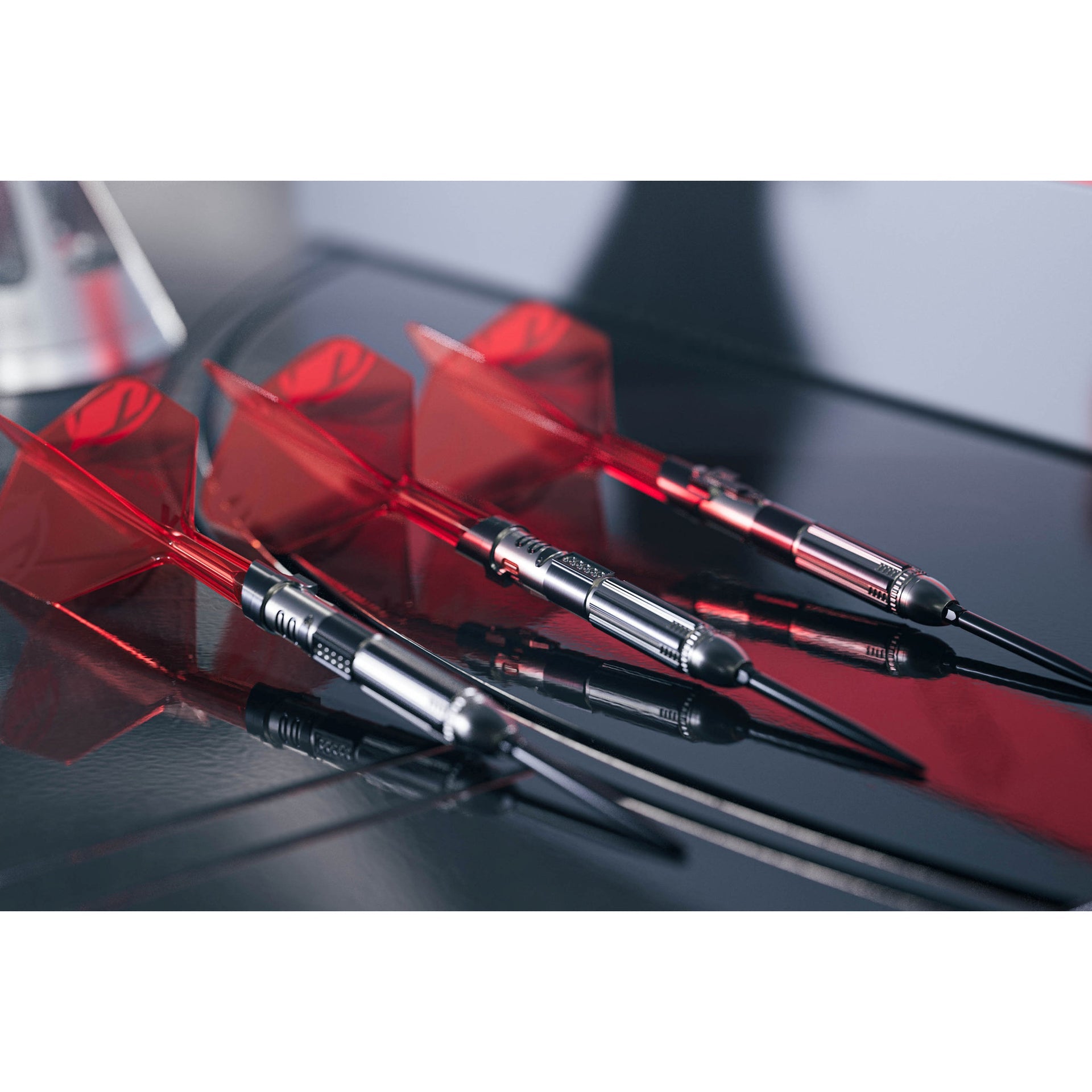 Three darts with red flights on a reflective surface Three darts with red flights on a reflective surface