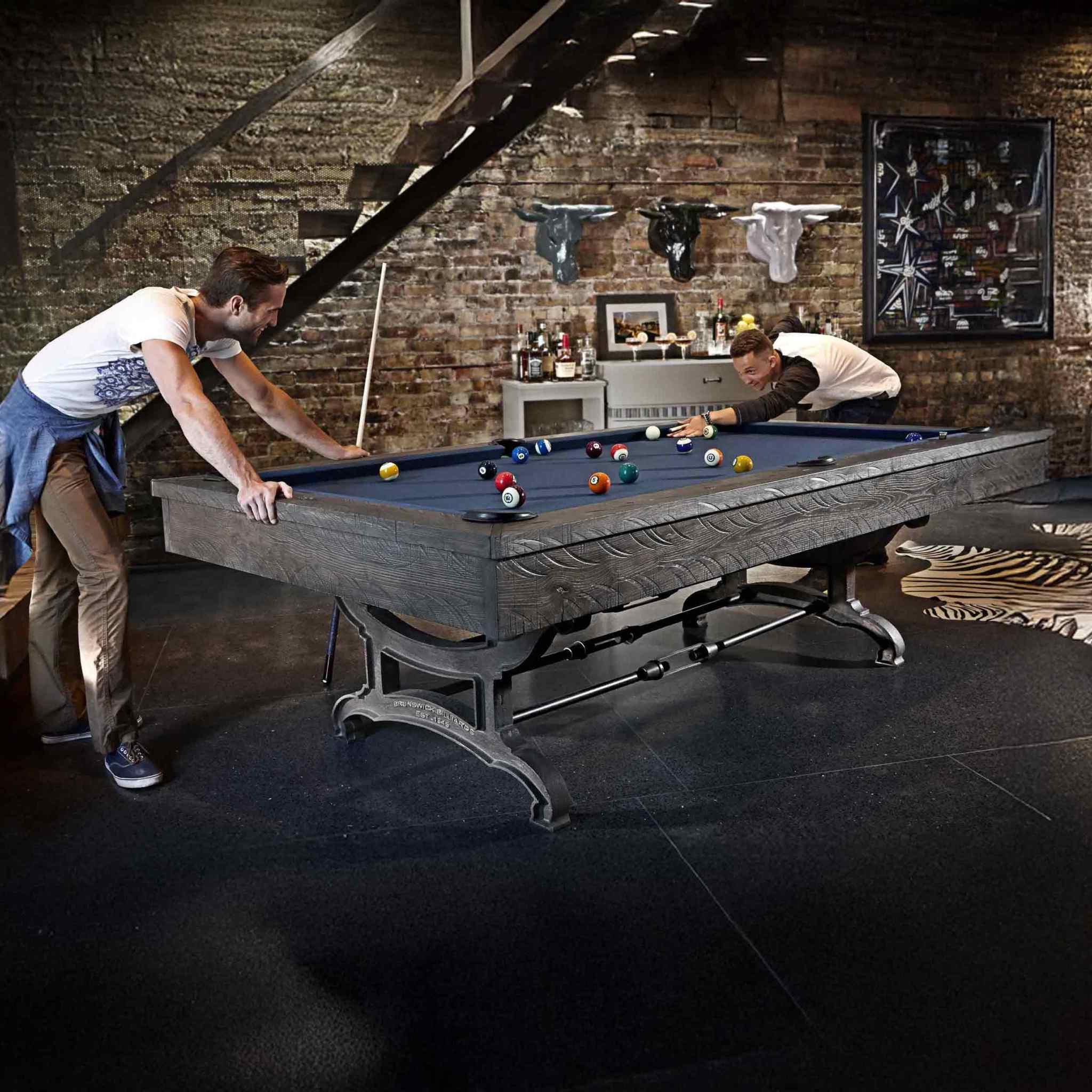Birmingham Pool Table by Brunswick Billiards with distressed finish and cast iron pedestal in industrial loft game room setting