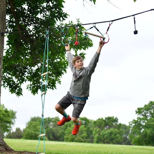 Boy using Slackers Ninjaline 36' Intro Kit outdoor hanging obstacle course with rings and rope holds Boy using Slackers Ninjaline 36' Intro Kit outdoor hanging obstacle course with rings and rope holds