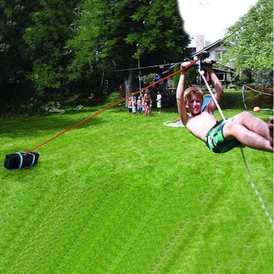 Child riding backyard zipline attached to Slackers Zipline Deluxe bungee brake kit with sandbag anchor