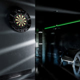 Dartboard on a wall with a dark room and green light in the background