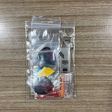 A clear plastic zip-top bag containing a small dart keychain set on a wood-grain tabletop. The set includes assorted dart Accessory Pack.  Side A