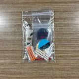A clear plastic zip-top bag containing a small dart keychain set on a wood-grain tabletop. The set includes assorted dart Accessory Pack. Side B