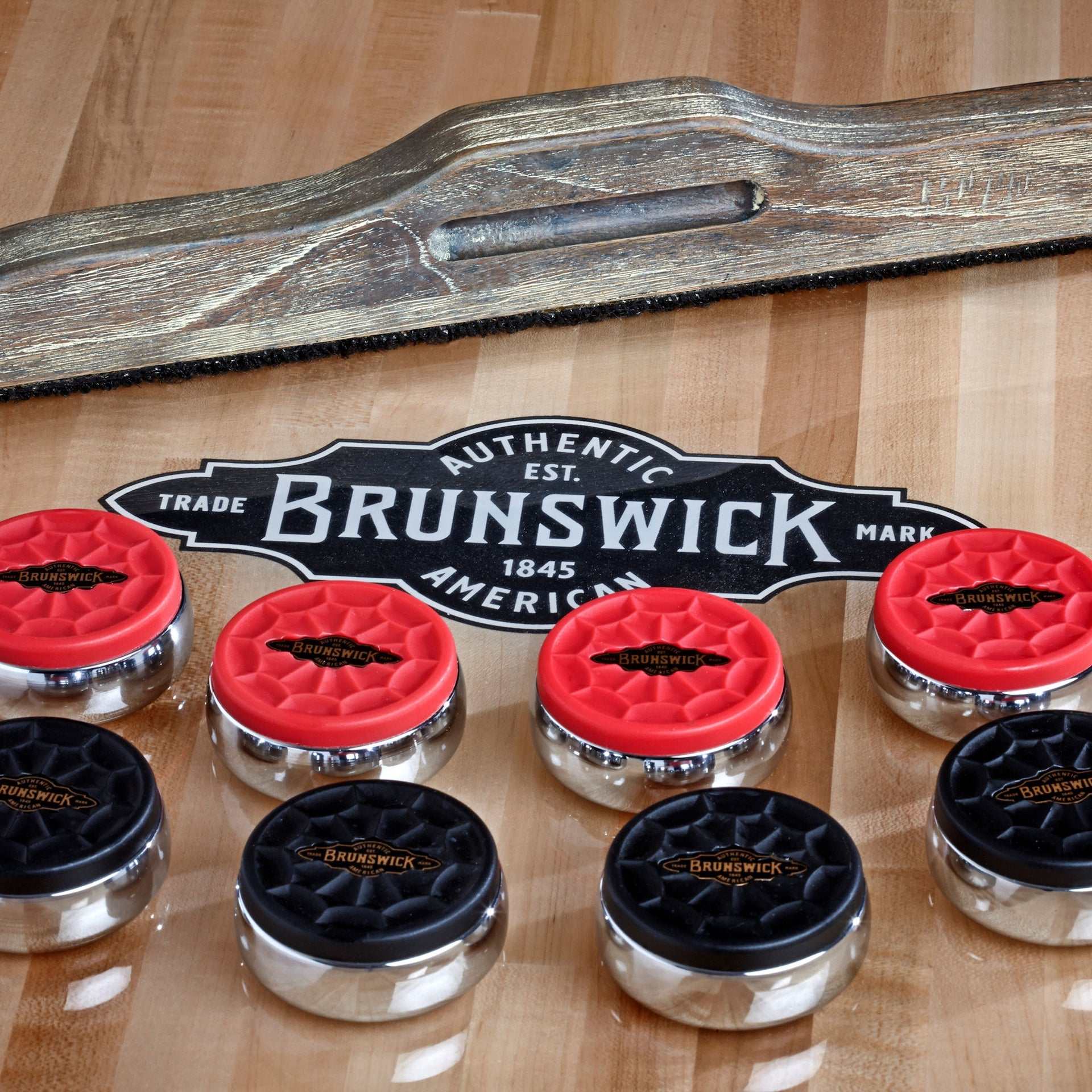 Brunswick Shuffleboard Rocks with chrome-plated red and black caps on wooden shuffleboard table