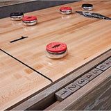 Brunswick Shuffleboard Rocks with red and black caps on wooden shuffleboard table