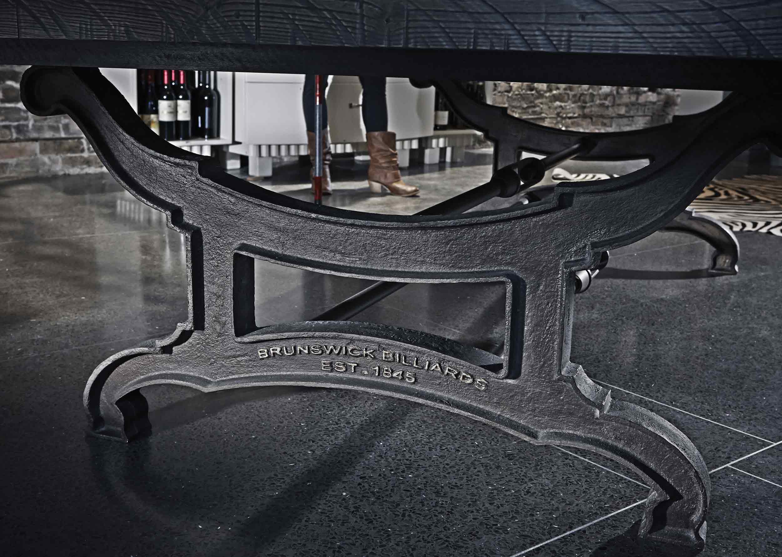 Close-up of Birmingham Pool Table cast iron decorative pedestal with Brunswick Billiards engraving on polished concrete floor
