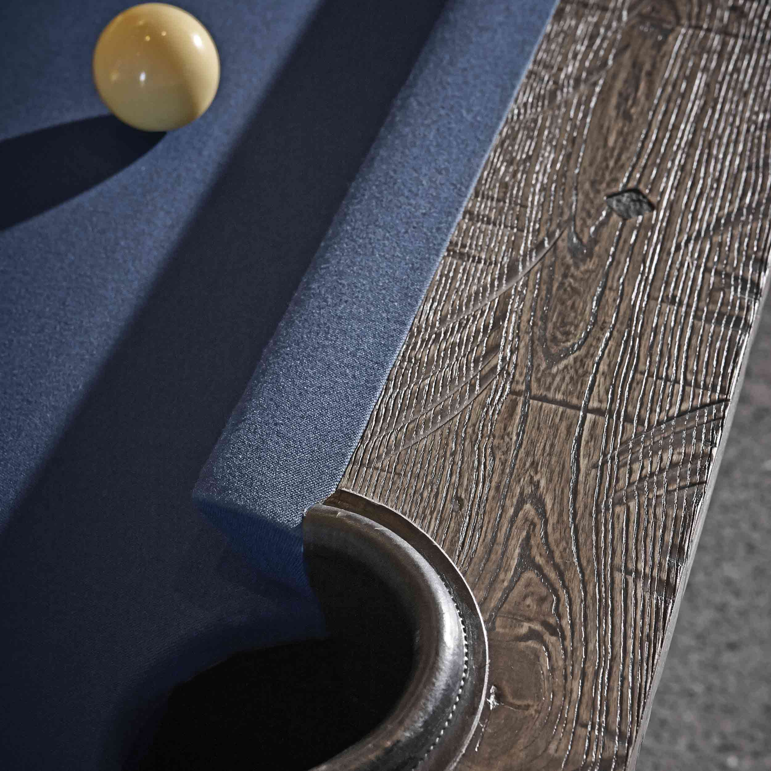 Close-up of Birmingham Pool Table corner showing distressed wood finish and dark blue woolen cloth with a cue ball nearby