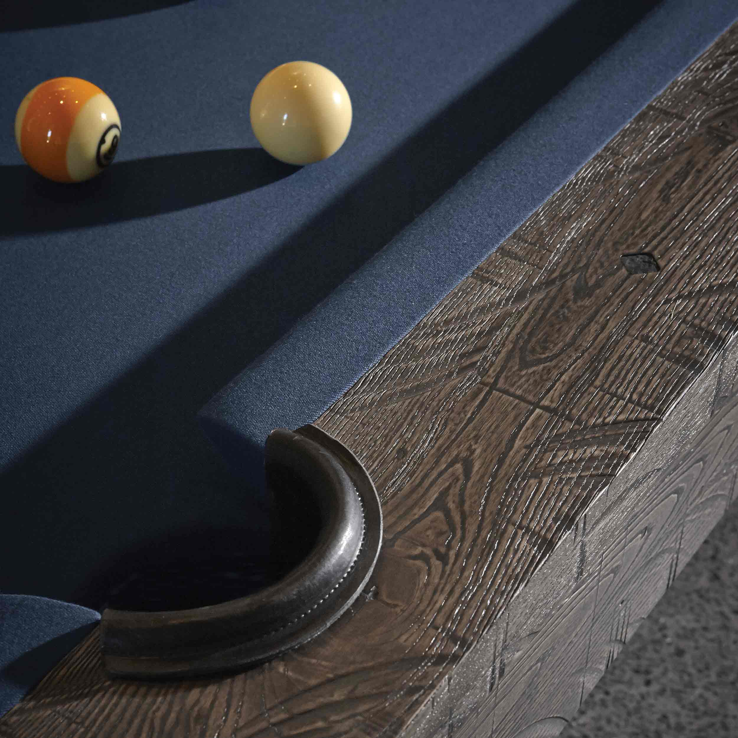 Close-up of Birmingham Pool Table corner featuring distressed wood finish and navy wool cloth with billiard balls on the table surface