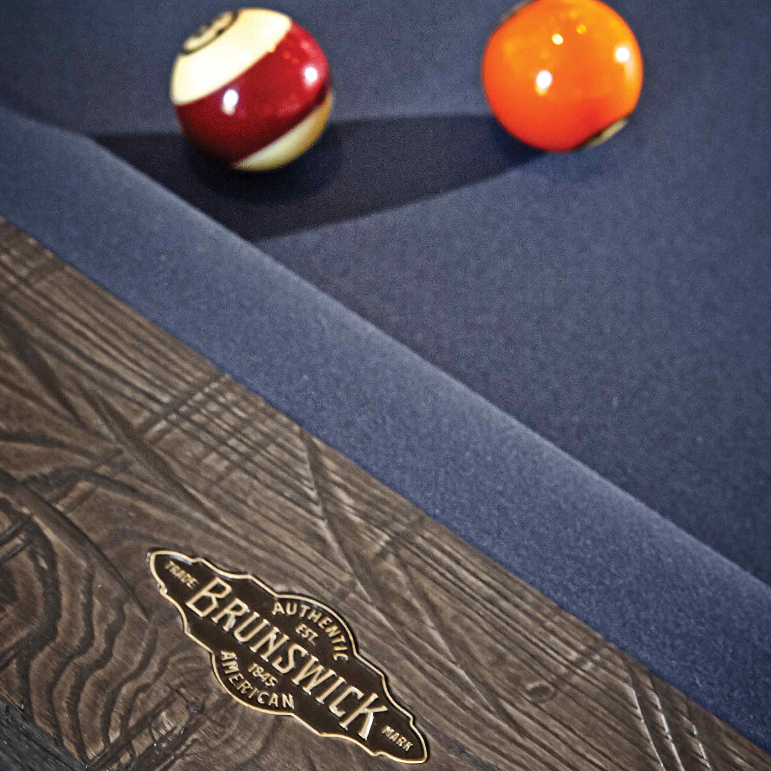 Close-up of Birmingham Pool Table by Brunswick with charcoal finish, hand-hammered rail sights, and blue woolen cloth showing billiard balls on the slate surface