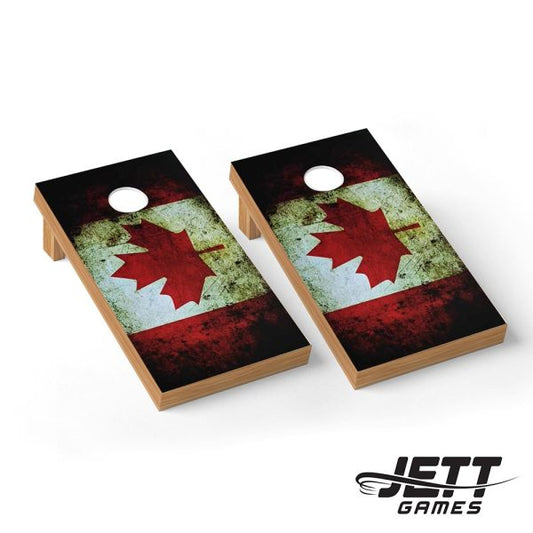 Two wooden cornhole boards with a distressed Canadian flag design, featuring a red maple leaf on a weathered red, white, and black background. The boards are shown on a clean white background with a JETT GAMES logo in the bottom right corner.