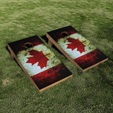 Two wooden cornhole boards with a distressed Canadian flag design, placed on a green grass lawn.