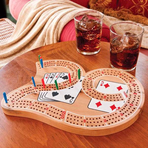Wooden 29 Cribbage Board with three tracks and colorful pegs on a table next to two glasses of cola