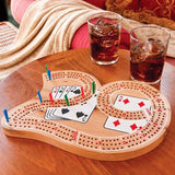 Wooden 29 Cribbage Board with three tracks and colorful pegs on a table next to two glasses of cola