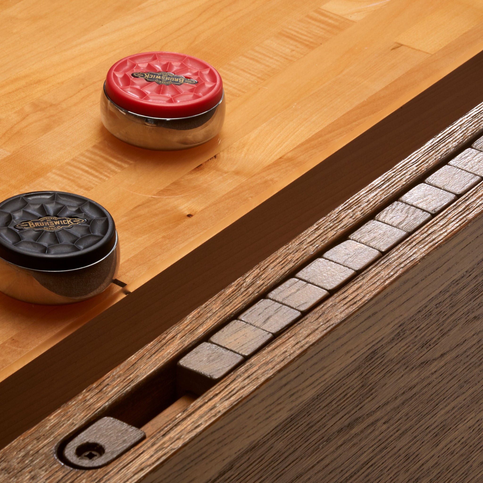 Two shuffleboard rocks on a wooden surface with a close-up of score unit