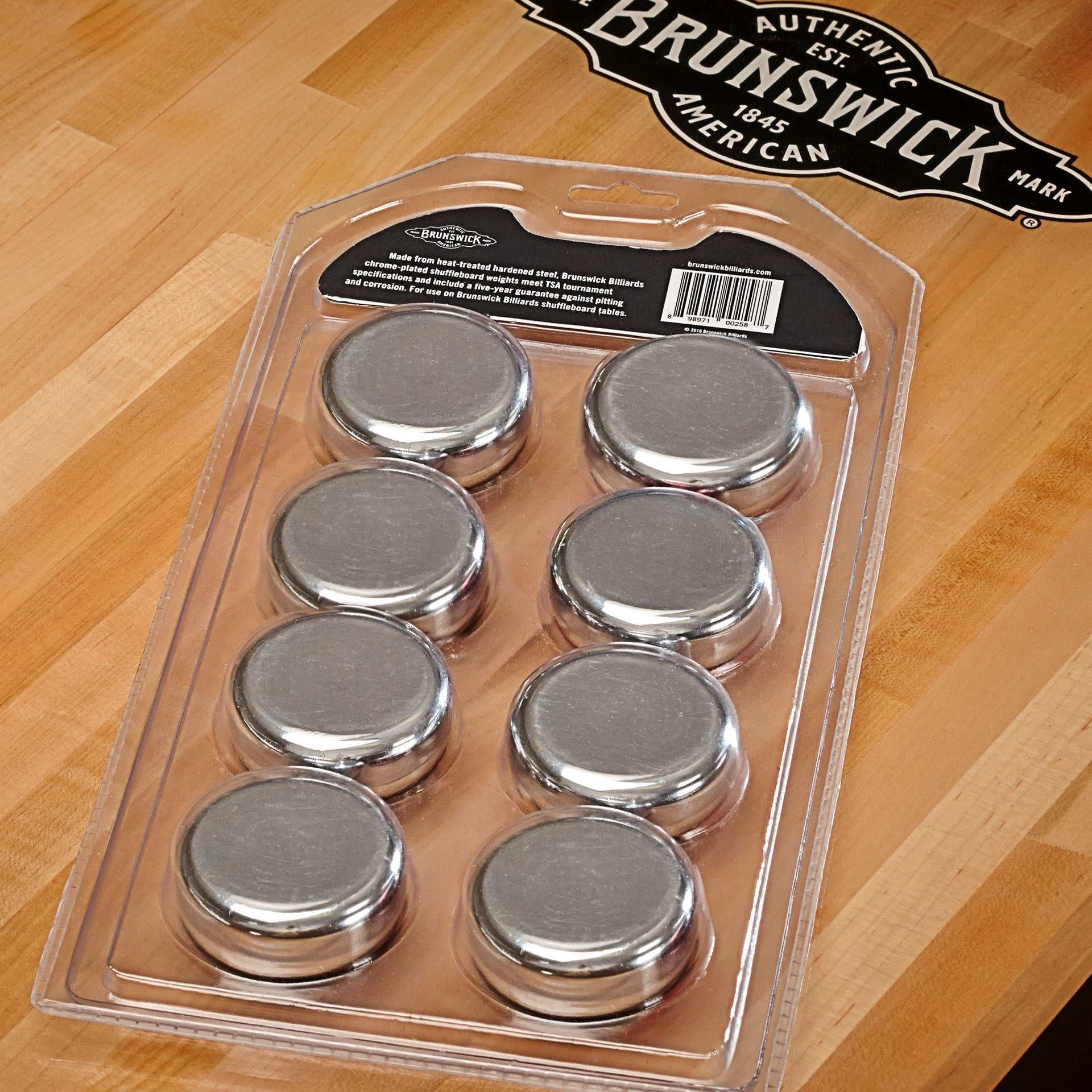Brunswick Shuffleboard Rocks chrome-plated steel weights in plastic tray on wooden shuffleboard table